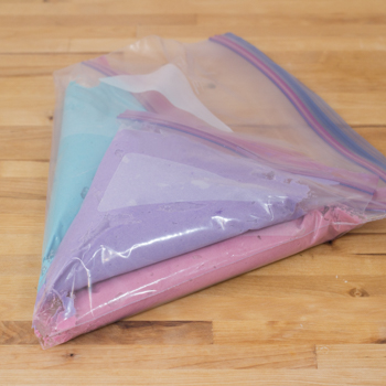 blue, purple, and pink icing colour bags together in one bigger plastic bag