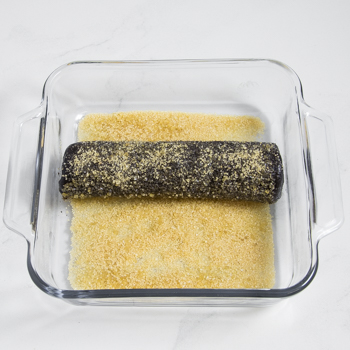  A log of dark dough in a glass baking dish lined with sanding or turbinado sugar