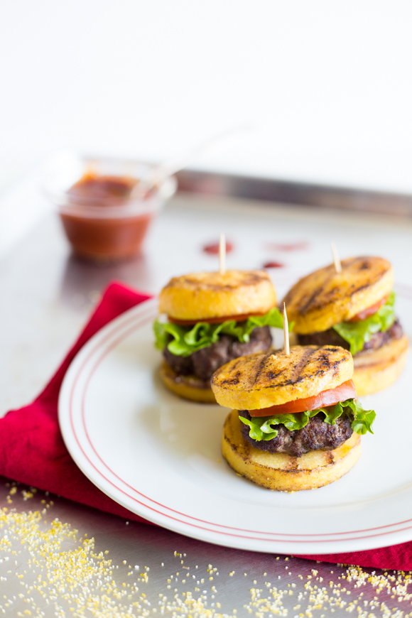 Polenta rounds used as burger buns on a plate. 