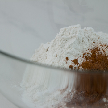 Flour, baking powder, baking soda, cinnamon, nutmeg, cloves, and salt in a bowl.